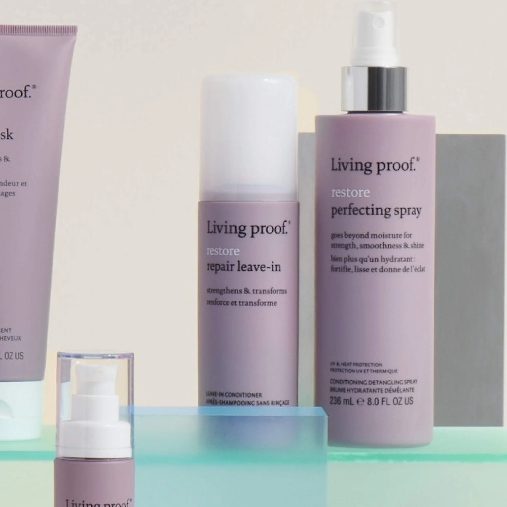 Flacon de Restore Repair Leave-In Living Proof sur fond clair, avec des cheveux brillants et bien démêlés en arrière-plan
