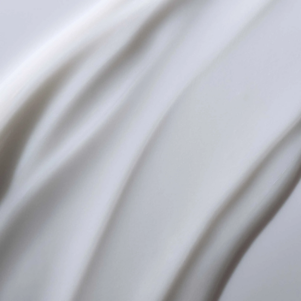 Flacon de Living Proof Full Conditioner posé sur fond neutre, avec des cheveux volumineux et brillants en arrière-plan