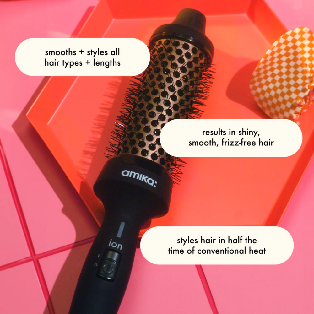 Brosse thermique Amika Blowout Babe 1,5″ posée sur fond blanc