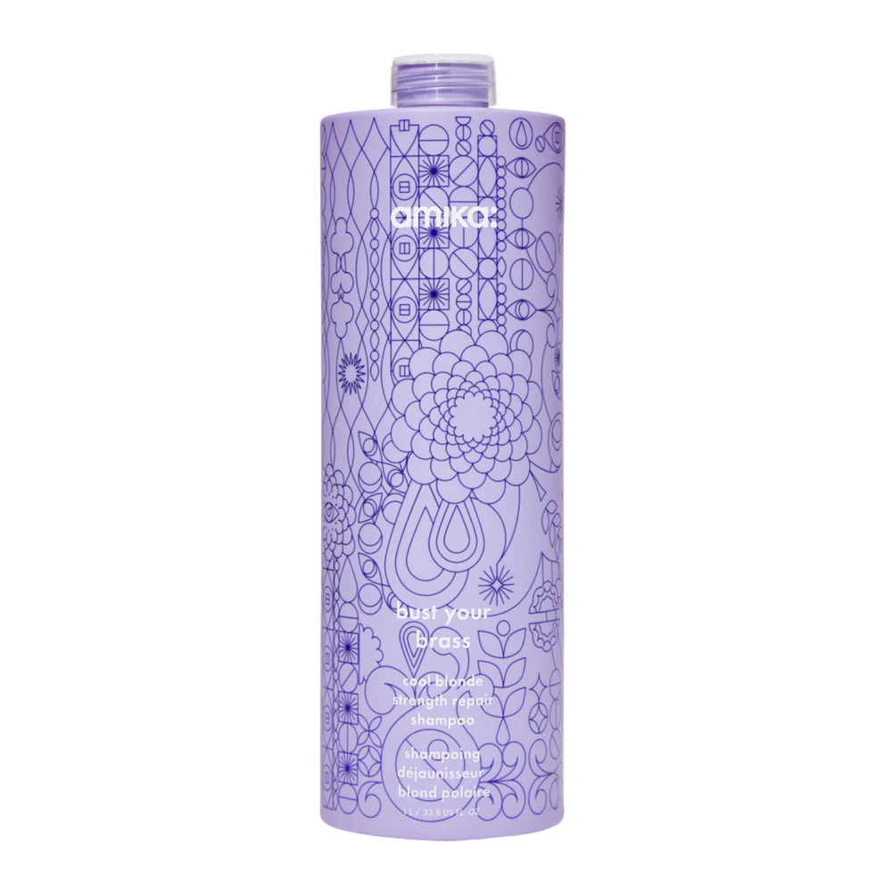 Flacon du shampoing Amika Bust Your Brass 275 ml posé sur fond blanc