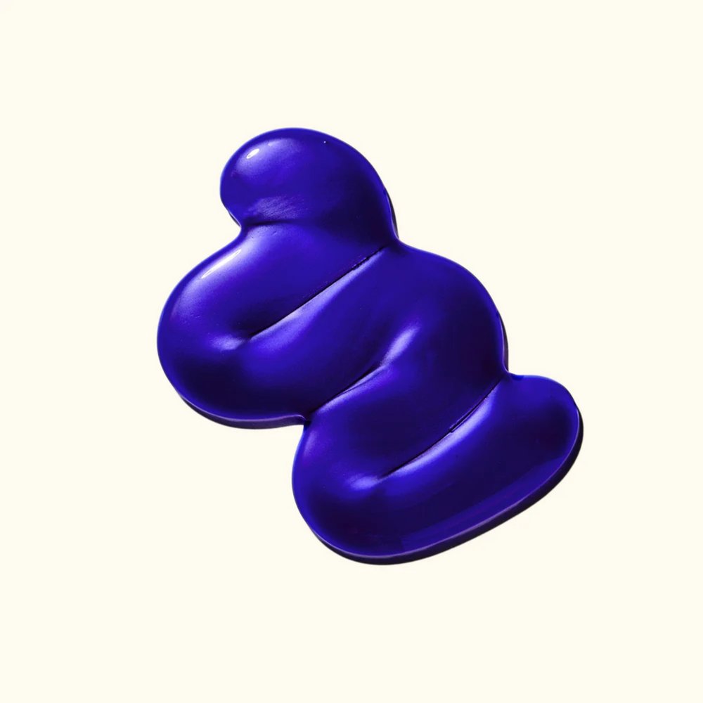 Flacon du shampoing Amika Bust Your Brass 275 ml posé sur fond blanc