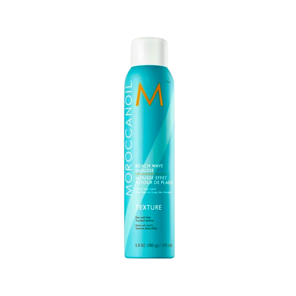 Flacon de la mousse retour de plage Moroccanoil « Texture Beach Waves » posé sur fond neutre