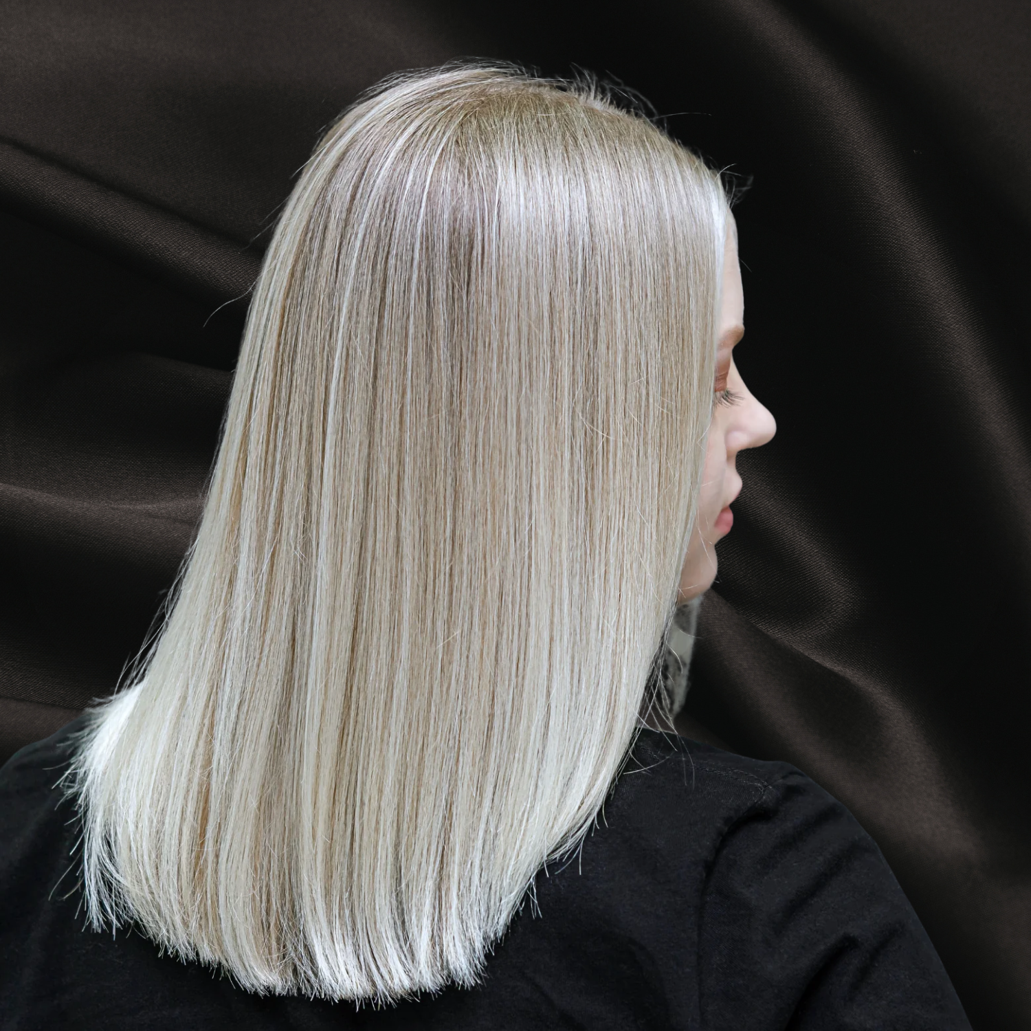 Femme de dos avec beau cheveux blond soyeux et lumineux sur fond noir texture satin