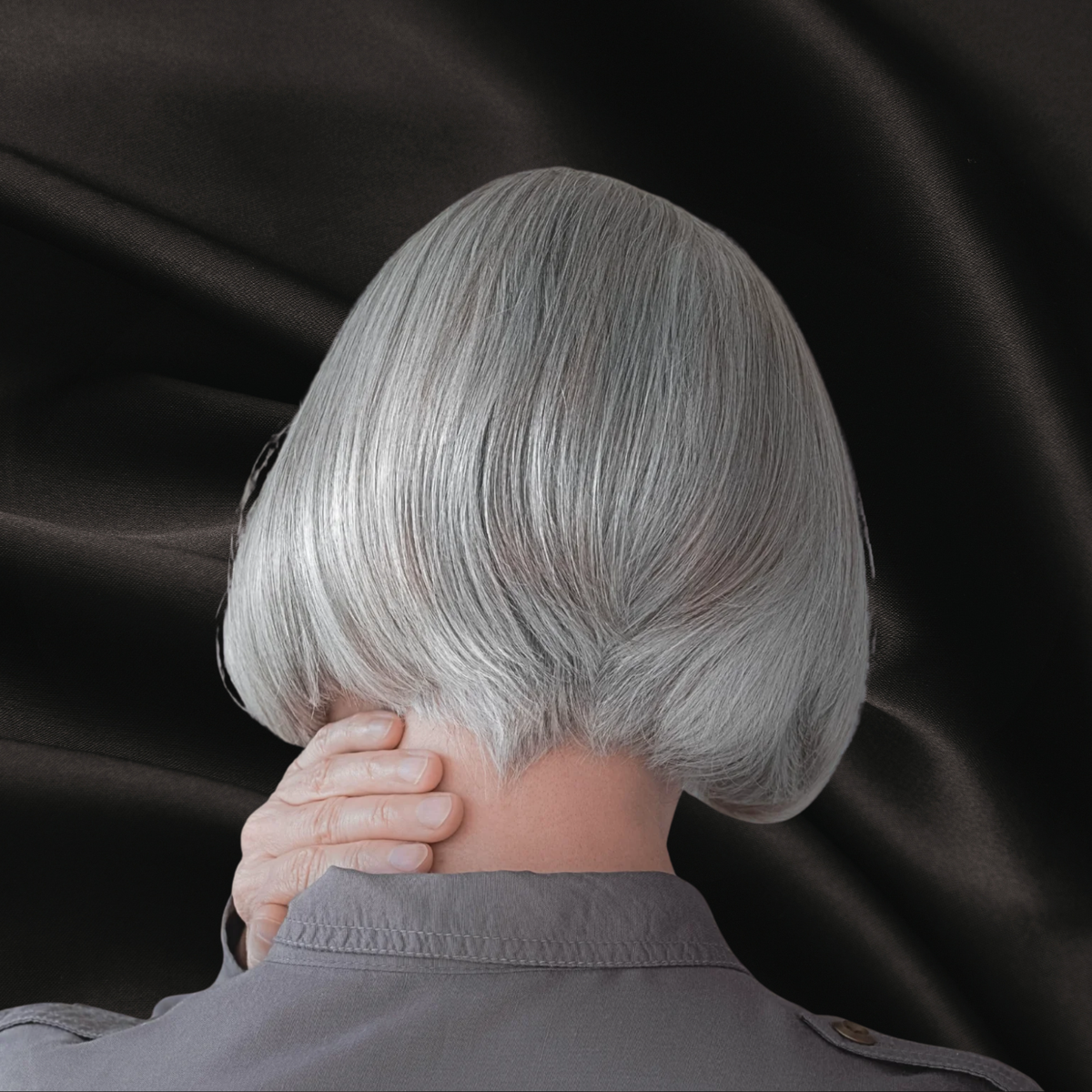 Femme de dos avec des cheveux gris sur fond noir texture satin