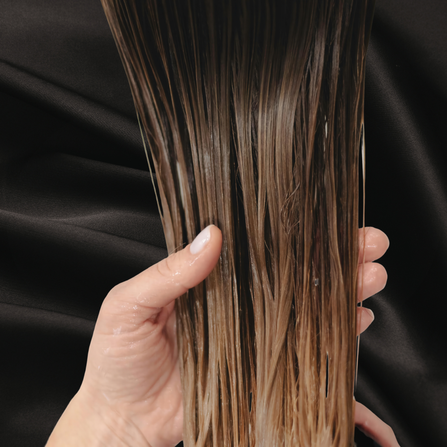Cheveux châtain revitalisé sur fond noir satin chez Cachet Urbain