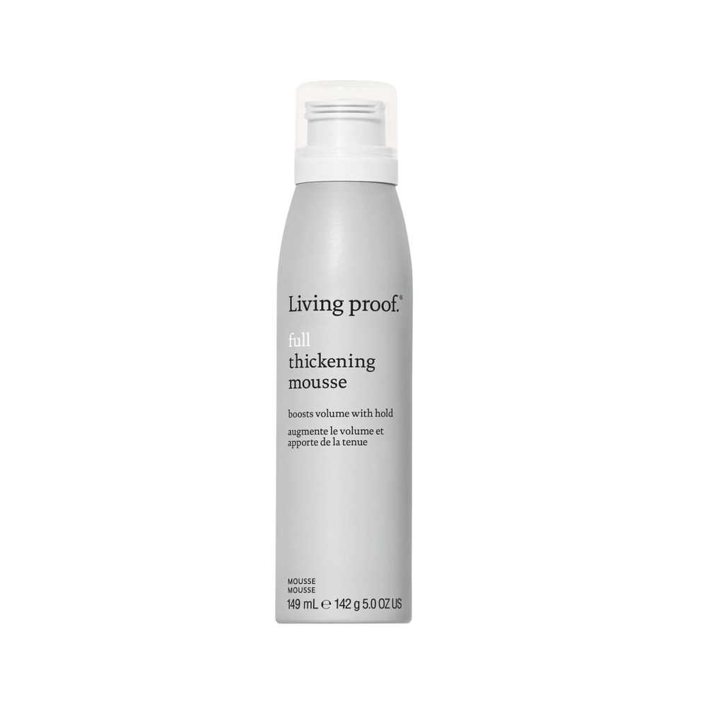 Flacon de Living Proof Full Thickening Mousse posé sur fond neutre, avec des cheveux volumineux et brillants en arrière-plan

