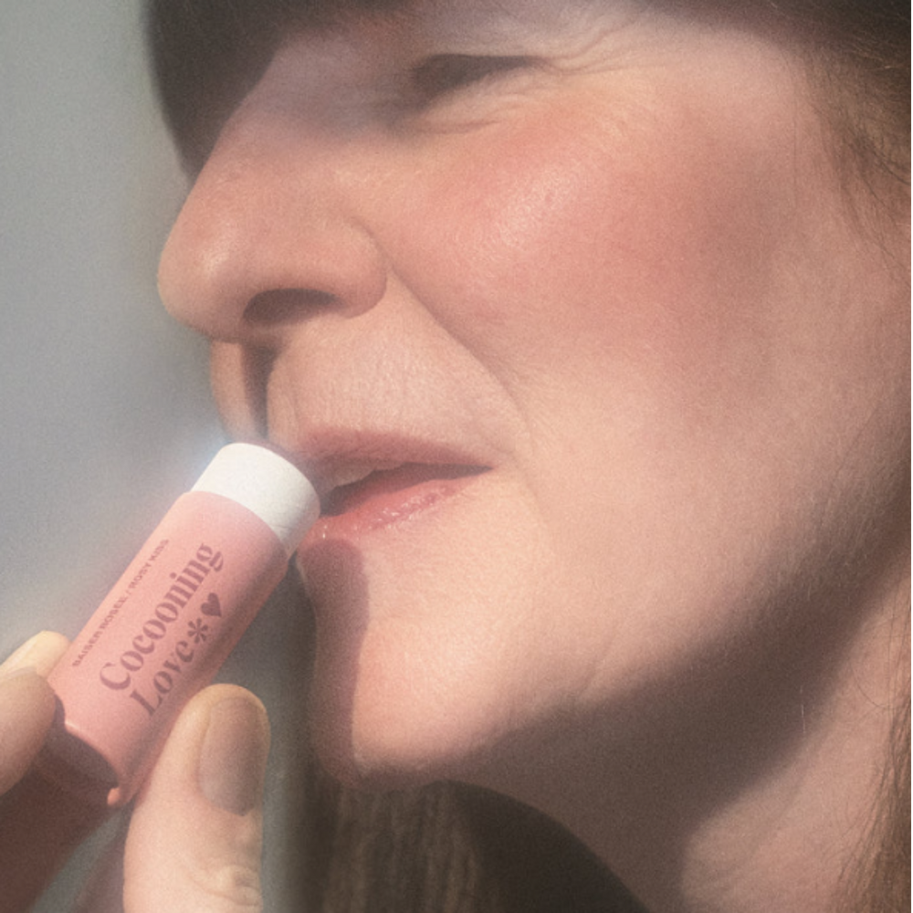 Baume à lèvres teinté Cocooning Love Rosy Kiss dans un tube en carton, teinte rosée délicate.