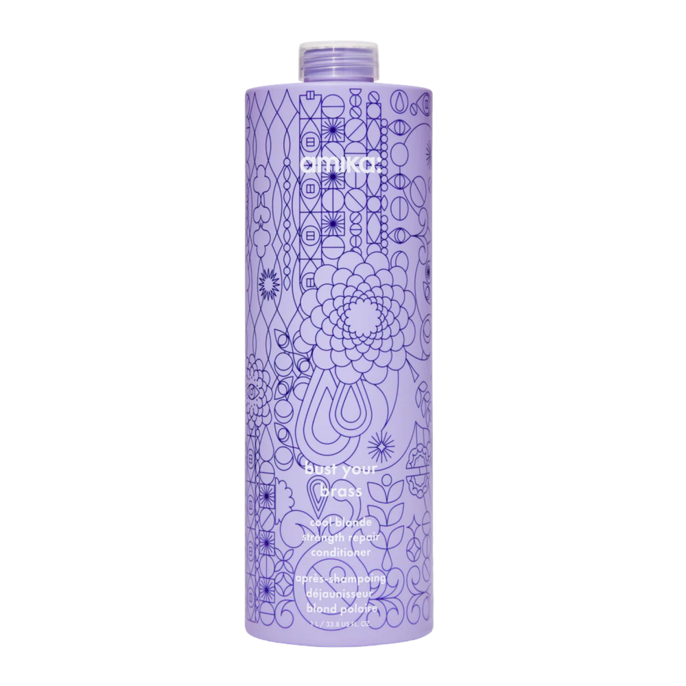 Flacon du conditionneur Amika Bust Your Brass 275 ml posé sur fond blanc

