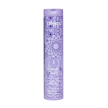 Flacon du shampoing Amika Bust Your Brass 275 ml posé sur fond blanc

