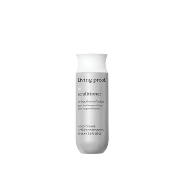 Flacon de Living Proof Full Conditioner posé sur fond neutre, avec des cheveux volumineux et brillants en arrière-plan

