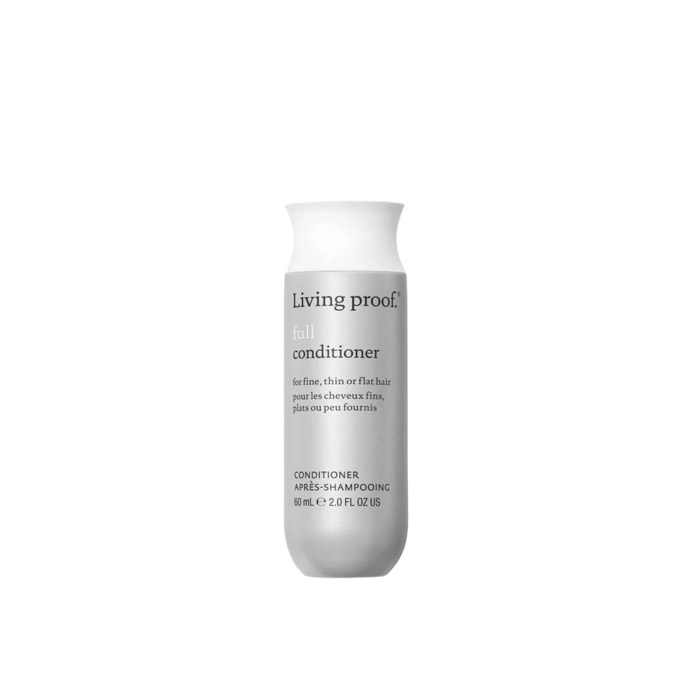 Flacon de Living Proof Full Conditioner posé sur fond neutre, avec des cheveux volumineux et brillants en arrière-plan

