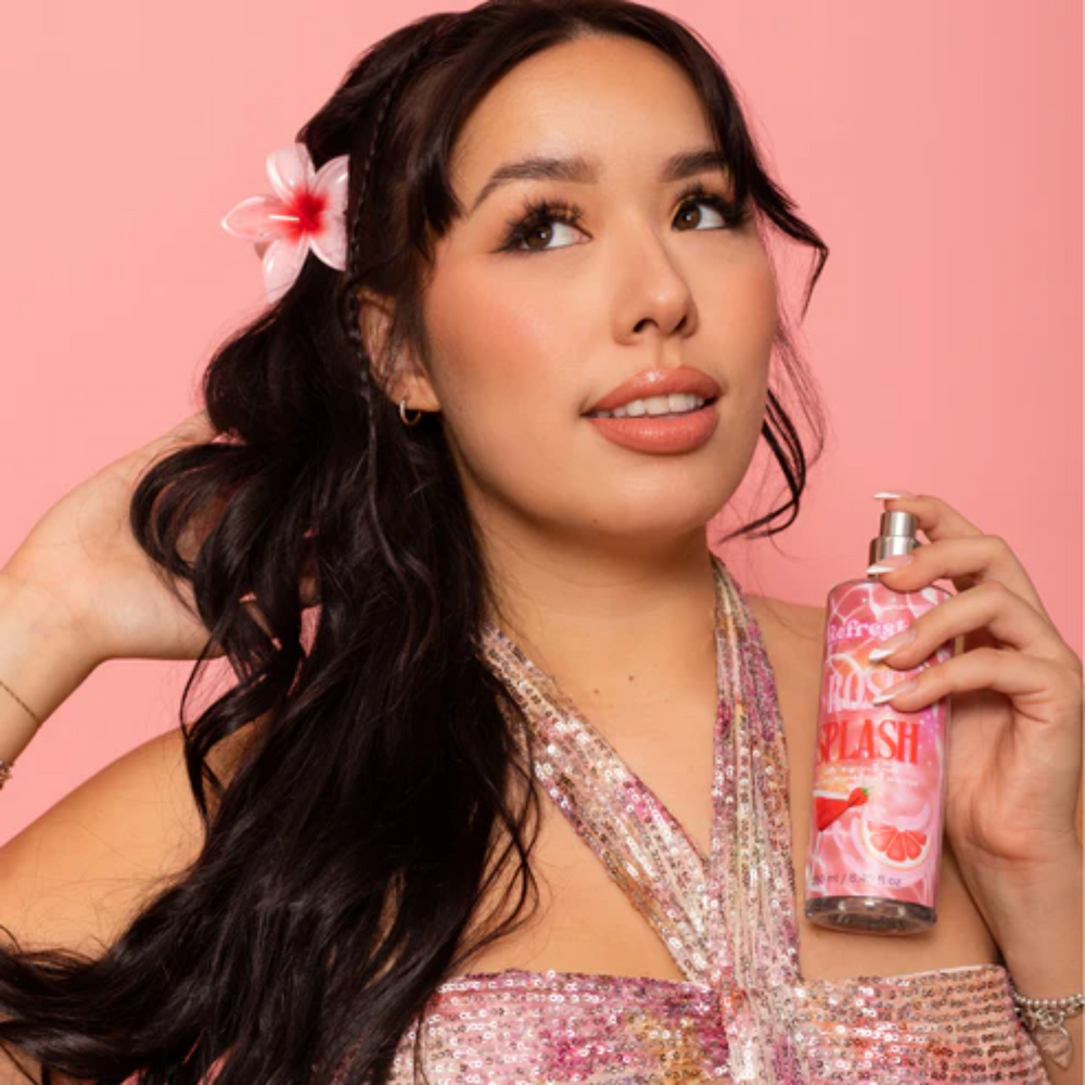 Flacon de brume corporelle Rosé Splash Refreshi posé sur fond pastel avec des touches de fruits et fleurs.

