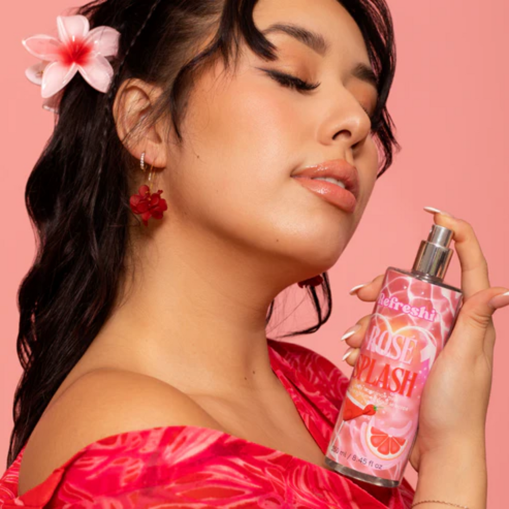 Flacon de brume corporelle Rosé Splash Refreshi posé sur fond pastel avec des touches de fruits et fleurs.

