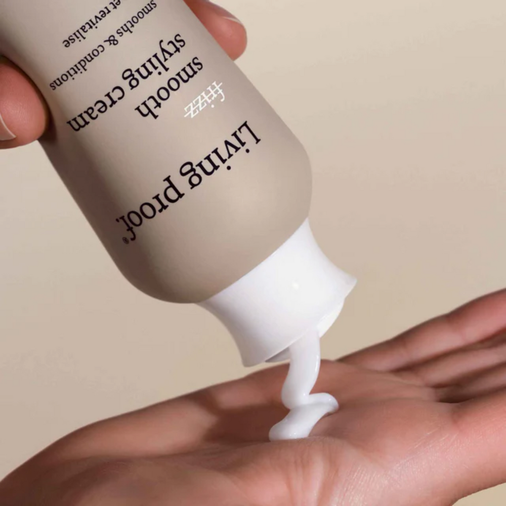 Flacon beige de la crème coiffante No Frizz Smooth Styling Cream par Living Proof, posé sur fond neutre, illustrant douceur, lissage et soin anti‑frisottis.

