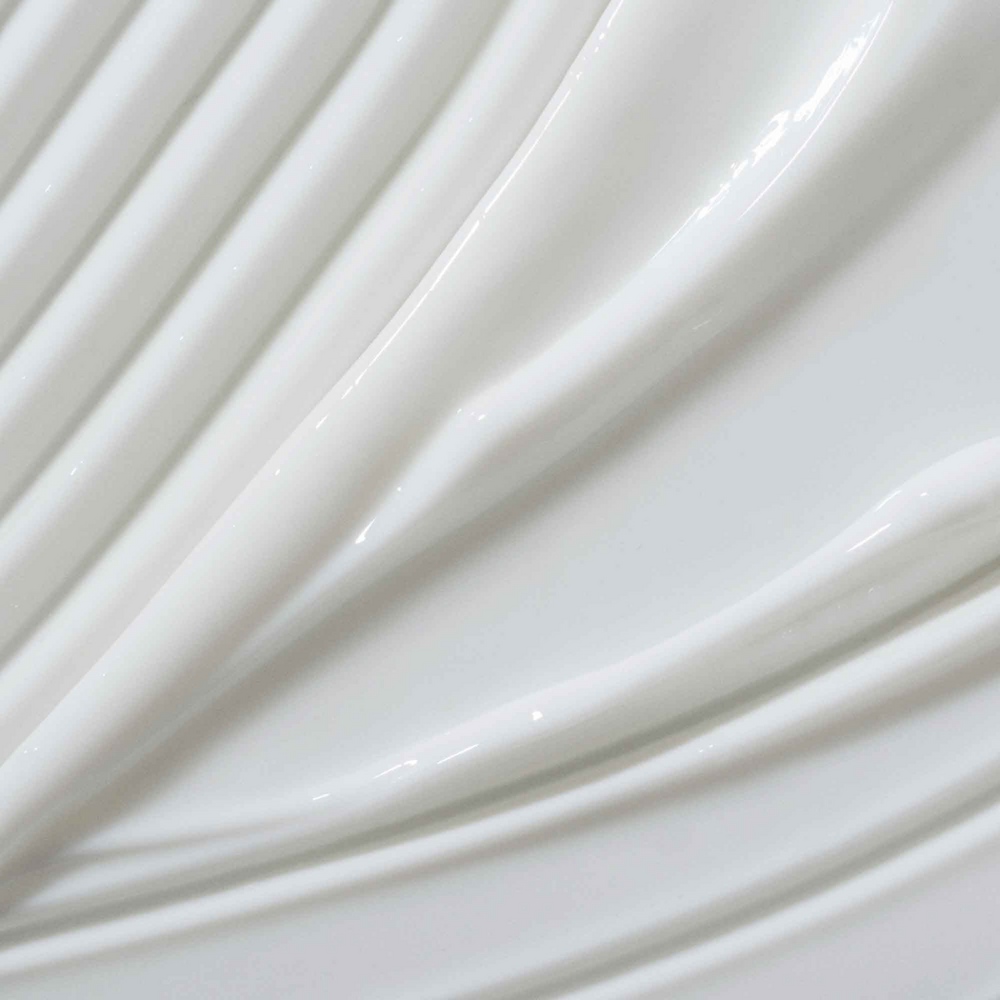Flacon de crème coiffante Living Proof posé sur une surface claire avec des cheveux brillants et volumineux en arrière-plan

