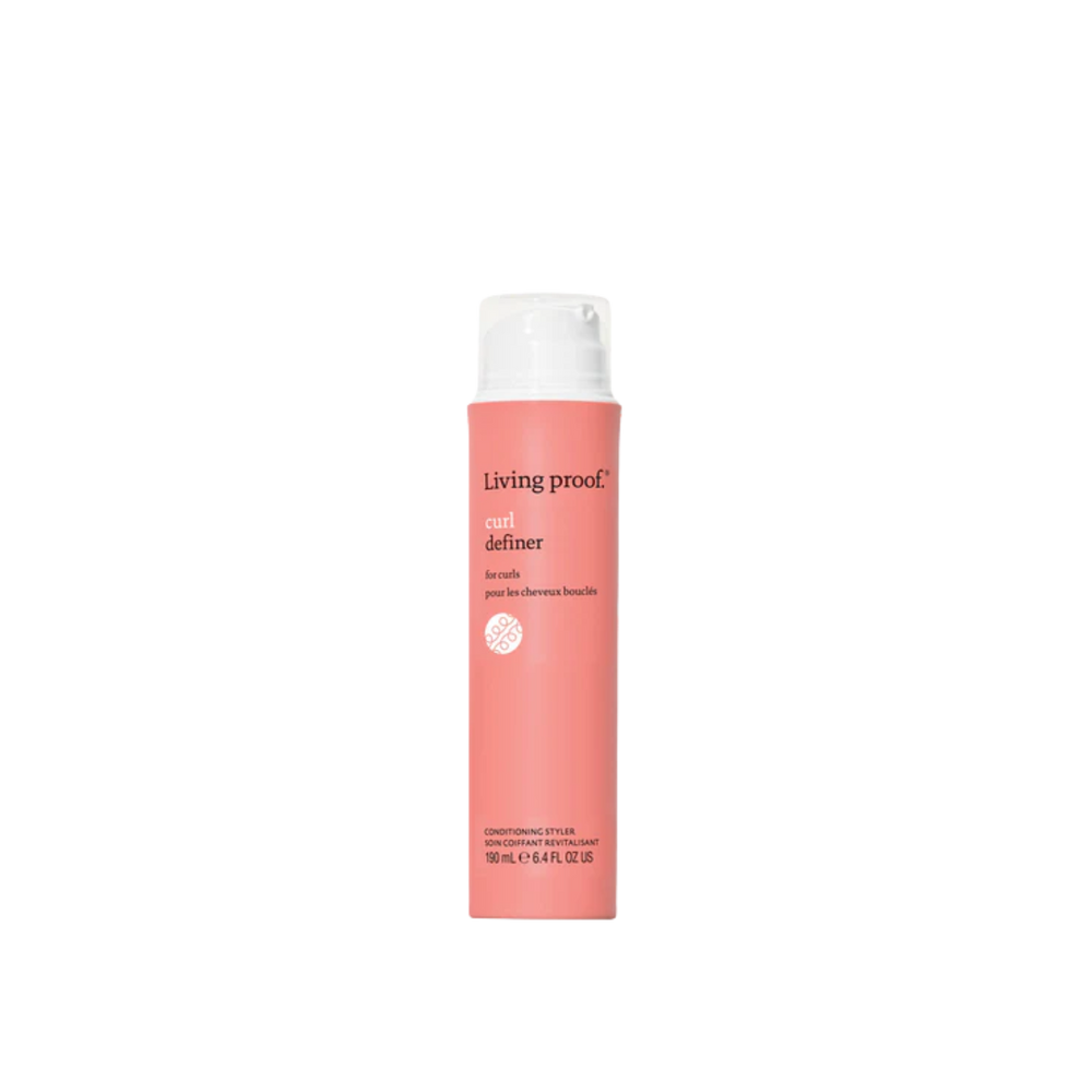 Tube corail du Curl Definer Living Proof avec pompe blanche, posé sur fond clair et montrant sa texture lisse et son design épuré.


