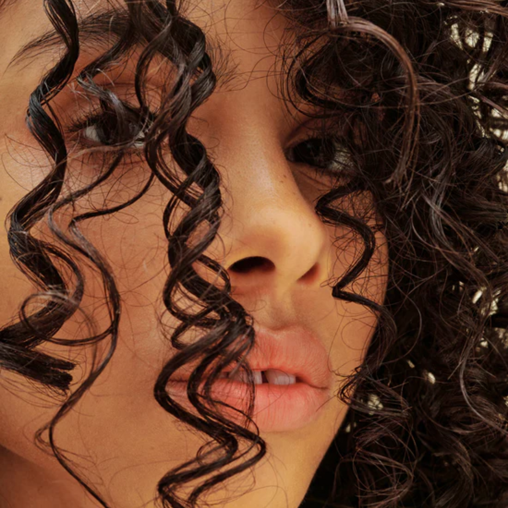 Flacon AG Care Liquid Effects Styling Gel sur fond neutre, cheveux bouclés définis en arrière-plan