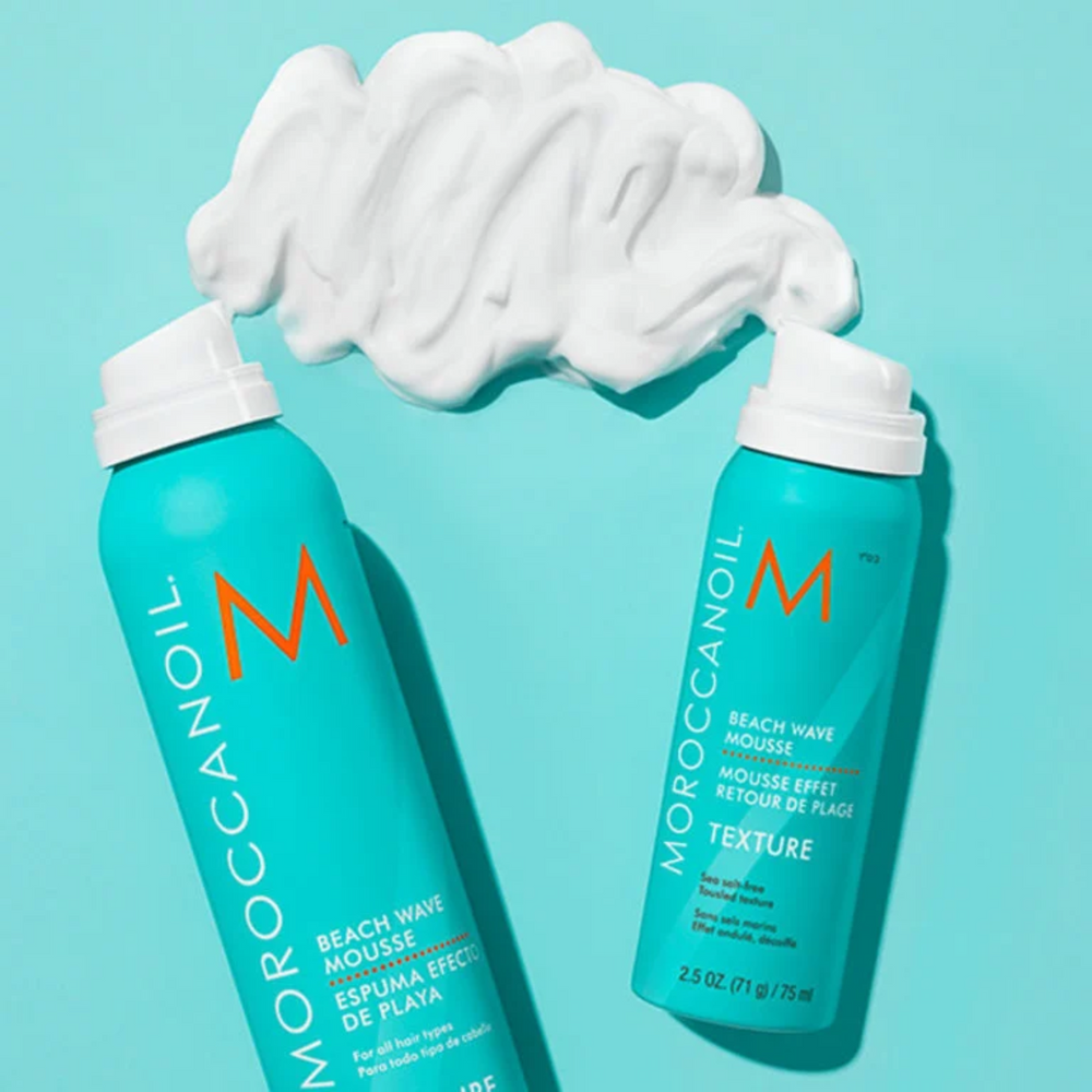 Flacon de la mousse retour de plage Moroccanoil « Texture Beach Waves » posé sur fond neutre