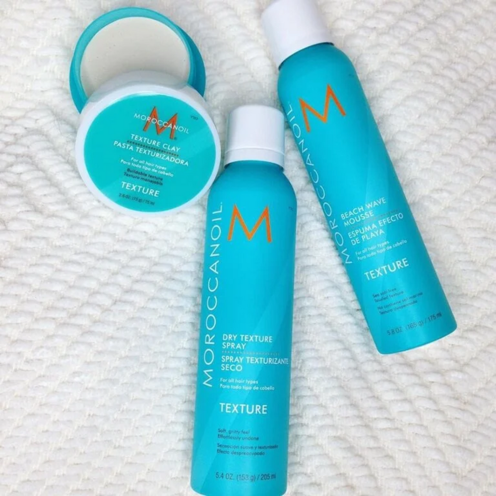 Flacon de la mousse retour de plage Moroccanoil « Texture Beach Waves » posé sur fond neutre