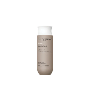 Flacon du shampoing No Frizz Living Proof blanc argenté, évoquant douceur, lissage et anti‑humidité, posé sur un fond clair minimaliste.

