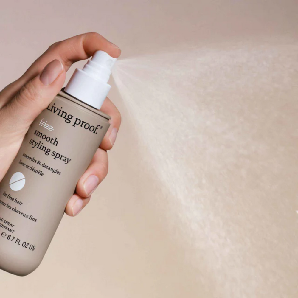 Flacon beige clair du spray coiffant No Frizz Smooth de Living Proof avec capuchon blanc, évoquant légèreté, lissage et contrôle des frisottis.


