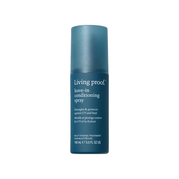 Flacon de spray sans rinçage Living Proof posé sur une surface claire, avec un fond neutre et des cheveux démêlés en arrière-plan

