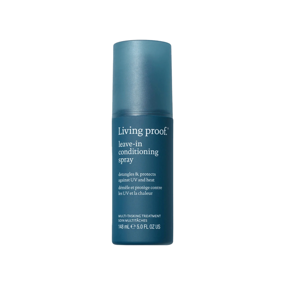 Flacon de spray sans rinçage Living Proof posé sur une surface claire, avec un fond neutre et des cheveux démêlés en arrière-plan

