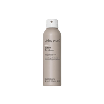 Flacon beige du spray No Frizz Instant De‑Frizzer posé sur une surface neutre, illustrant un soin express pour lisser les frisottis et raviver la brillance.

