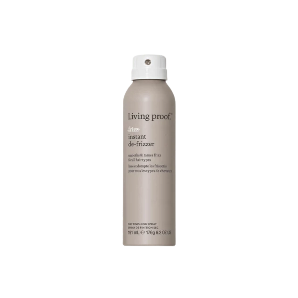 Flacon beige du spray No Frizz Instant De‑Frizzer posé sur une surface neutre, illustrant un soin express pour lisser les frisottis et raviver la brillance.

